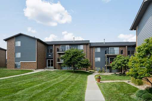 Apartment complex with a grassy front yard and a walkway.