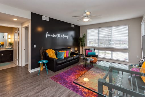 an open living room with large windows and a black accent wall. pops of color throughout the room