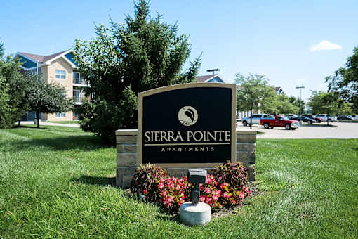A sign for Sierra Pointe Apartments is surrounded by flowers and greenery.
