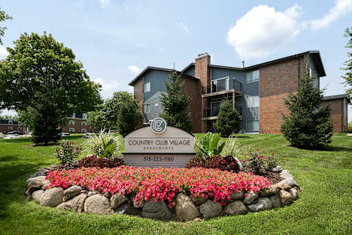 A sign for Country Club Village Apartments is in front of a building.