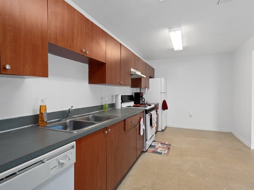 a kitchen with wood cabinets and a sink and a stove and a refrigerator at The Groves at Wimauma Apartments , Wimauma