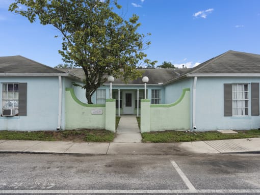 a white and green house with a tree in front of it at The Groves at Wimauma Apartments , Wimauma, FL, 33598