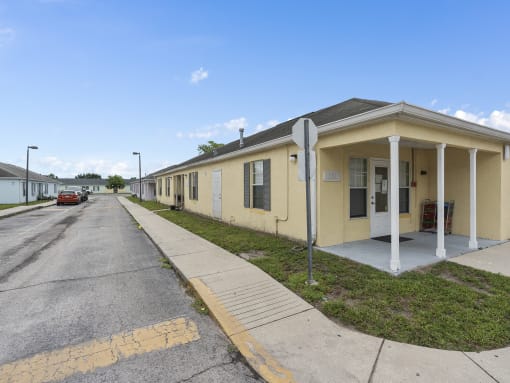a yellow building with a sidewalk and a street at The Groves at Wimauma Apartments , Florida