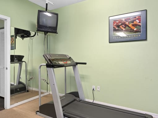 a treadmill in a gym with a tv on the wall at The Groves at Wimauma Apartments , Wimauma, FL