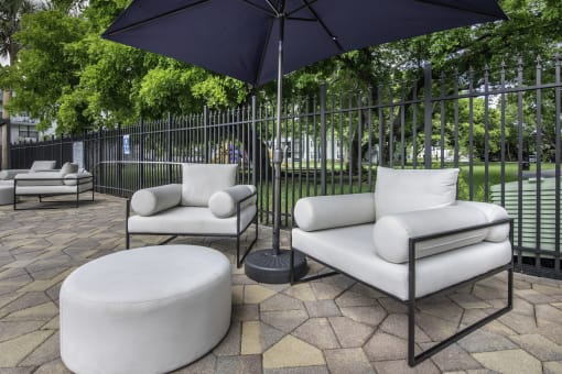 a patio with two white couches and two black umbrellas  at Club at Emerald Waters, Florida