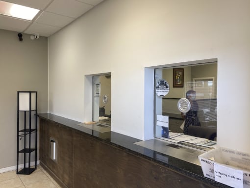 a reception desk with a large window and a small window next to it at Colonial Apartments, Orlando, FL