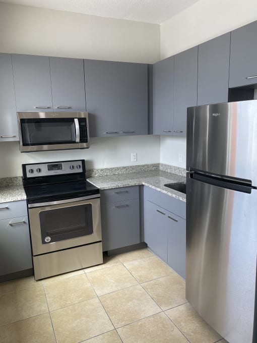 a kitchen with gray cabinets and stainless steel appliances at Colonial Apartments, Orlando, FL