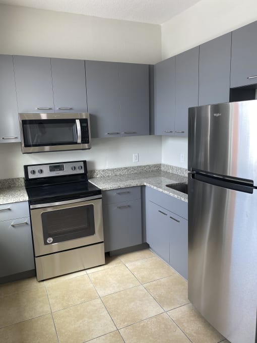 a kitchen with gray cabinets and stainless steel appliances at Colonial Apartments, Orlando, FL 32808