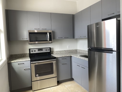 a kitchen with gray cabinets and stainless steel appliances at Colonial Apartments, Florida