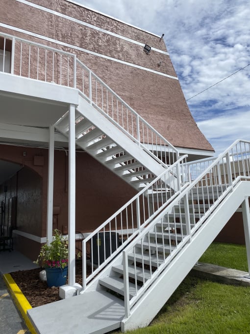a white staircase on the side of a building with a cloudy sky in the background at Colonial Apartments, Orlando, FL