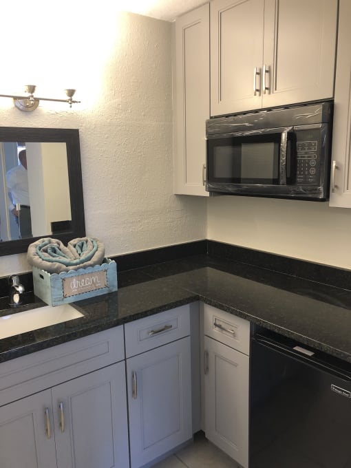 a kitchen with white cabinets and black countertops at Colonial Apartments, Orlando Florida