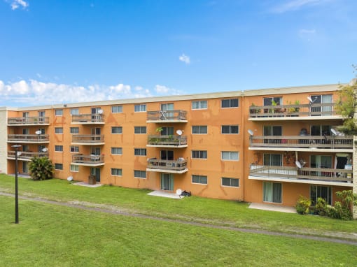 a large apartment building with balconies and a green lawn at Cypress Grove, Lauderhill, 33313