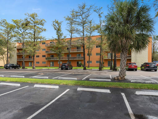 an apartment building with a parking lot and palm trees at Cypress Grove, Florida