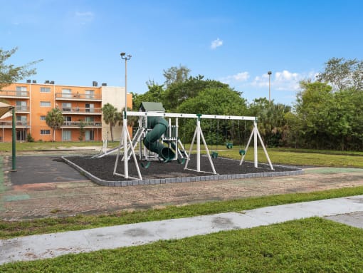 a swing set in a park in front of a building at Cypress Grove, Lauderhill