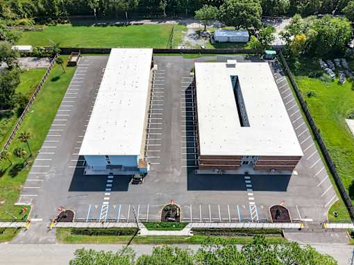 An aerial view of a parking lot with two buildings.