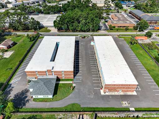 A large parking lot is surrounded by a building and a grassy area.