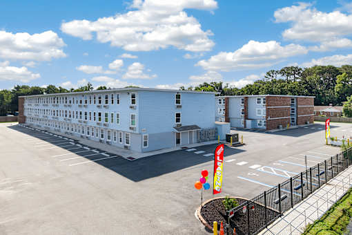 A large white building with a black fence and a yellow sign with red letters.