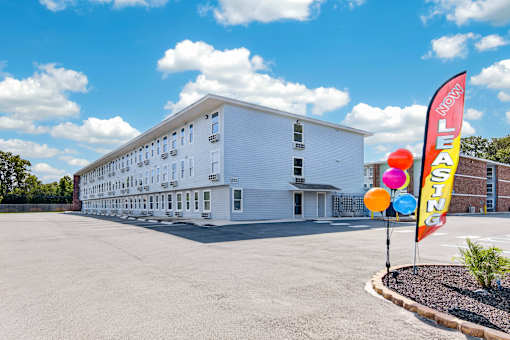 A white building with a sign that says "LEASING" in front of it.