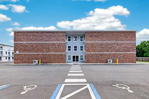 A parking lot with a building in the background and a crosswalk in the foreground.