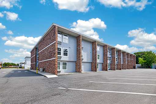 A large parking lot in front of a multi-story brick building.
