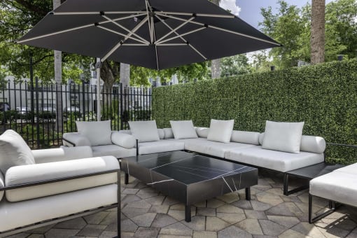 an outdoor patio with white couches and a black coffee table  at Club at Emerald Waters, Hollywood, 33021