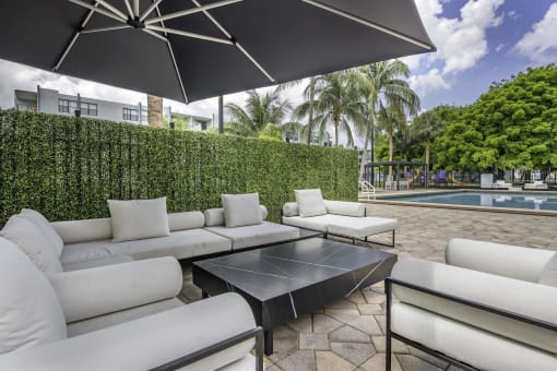 a patio with couches and a coffee table and a pool in the background  at Club at Emerald Waters, Hollywood, FL, 33021