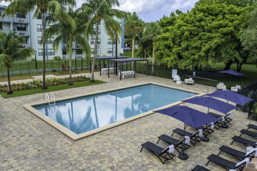 a resort style swimming pool with lounge chairs and umbrellas  at Club at Emerald Waters, Hollywood, FL, 33021