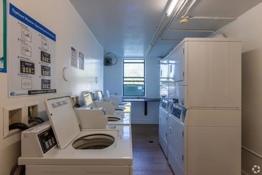 a laundry room with a row of washers and dryers  at Club at Emerald Waters, Hollywood, FL, 33021