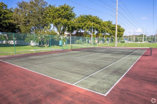 a tennis court with a fenced in area and trees in the background  at Club at Emerald Waters, Florida, 33021