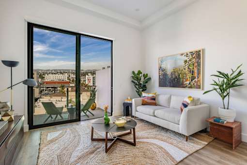 A living room with a large window overlooking a cityscape at WM by CLG, Los Angeles, CA 90232  