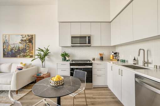 A modern kitchen with white cabinets and a black countertop at WM by CLG, Los Angeles  