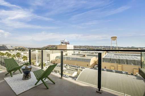 A balcony with two green chairs and a table at WM by CLG, Los Angeles, CA 90232  
