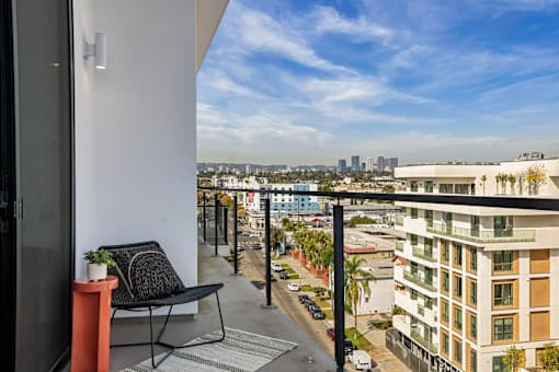 A balcony with a chair and table overlooks a city street at WM by CLG, Los Angeles, 90232  
