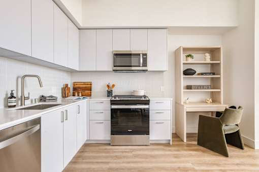 A modern kitchen with white cabinets and a wooden shelf at WM by CLG, Los Angeles California  