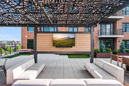 A modern outdoor seating area with a large screen displaying a landscape.