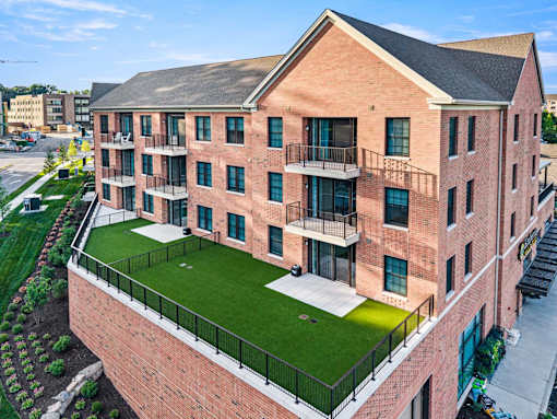 A red brick apartment building with a green lawn in the front.