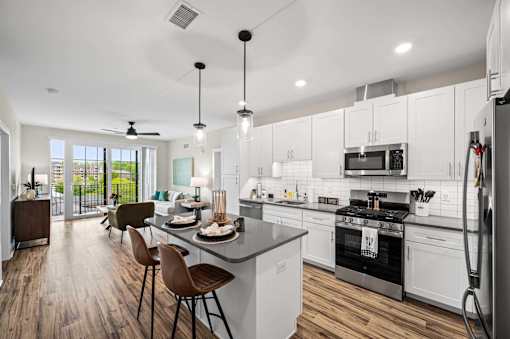 A modern kitchen with white cabinets and a wooden floor.