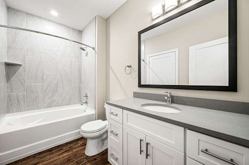 A white toilet sits in a bathroom next to a white bathtub.
