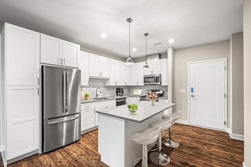 A modern kitchen with white cabinets and a wooden floor.