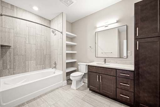 A bathroom with a tub, toilet, sink, and mirror.