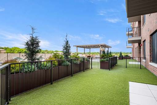 A patio with a black fence and a green lawn.
