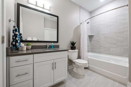 A bathroom with a white toilet, a sink, a mirror, and a bathtub.