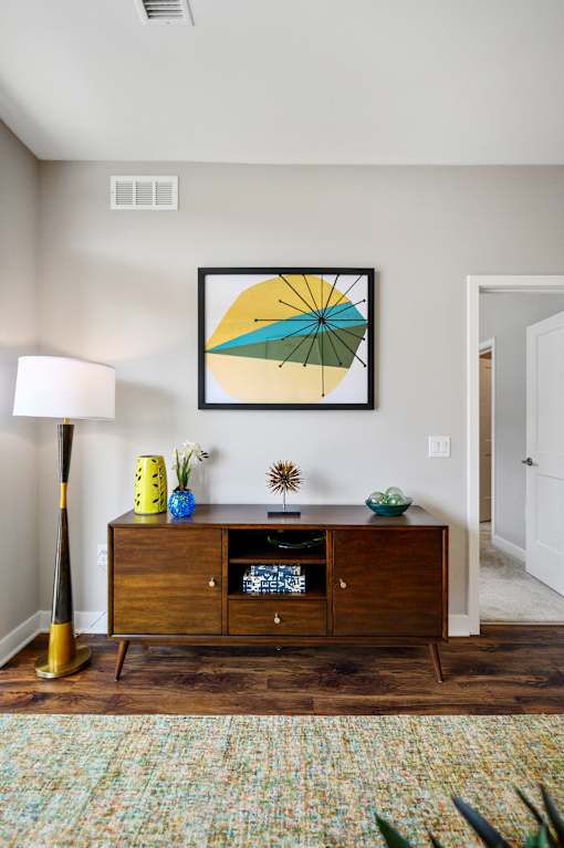 A picture of a yellow umbrella stands next to a wooden cabinet with a framed picture above it.