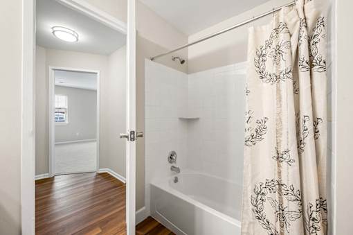 A bathroom with a shower and a wooden floor.