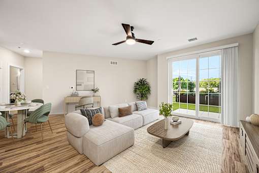 A living room with a sofa, a coffee table, a dining table, and a ceiling fan.