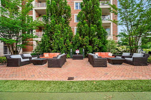 A patio with a table and chairs is surrounded by trees and apartment buildings.