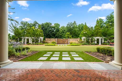 A garden with a brick pathway leading to a white archway.