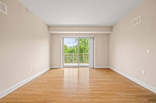 A room with wooden floors and a sliding glass door leading to a backyard.