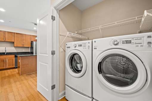A white door is open to reveal a laundry room with a washer and dryer.