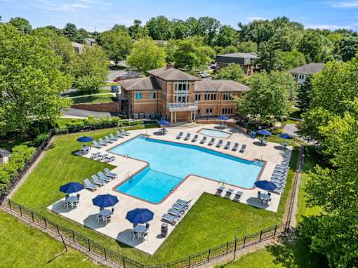 A large swimming pool surrounded by lawn chairs and umbrellas.